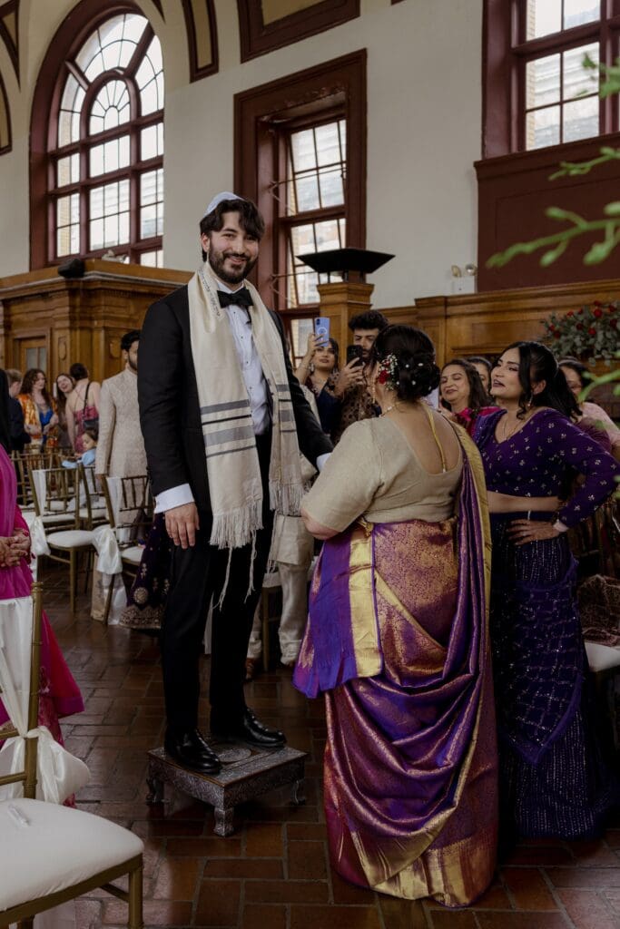 Bride's mother welcoming the groom during the ceremony at a Hindu Jewish wedding
