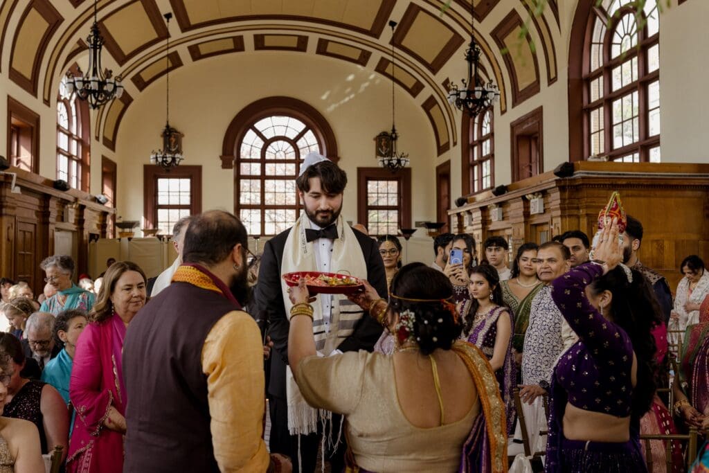 Bride's mother welcoming the groom during the ceremony at a Hindu Jewish wedding