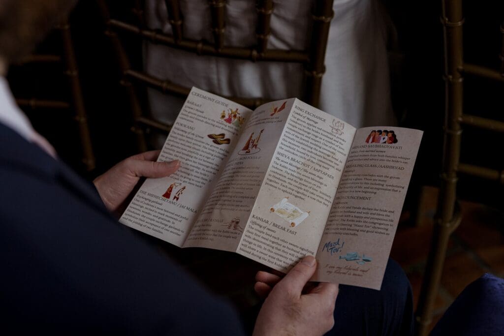 Close up of a guest reading the ceremony pamphlet at a Hindu Jewish wedding