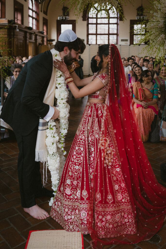 Bride placing garland around the groom's neck during a Hindu Jewish wedding ceremony