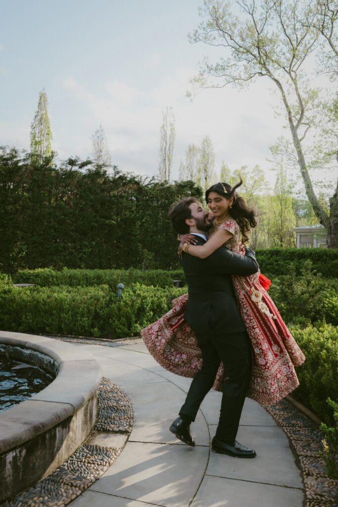 Groom spinning the bride around in his arms in a garden