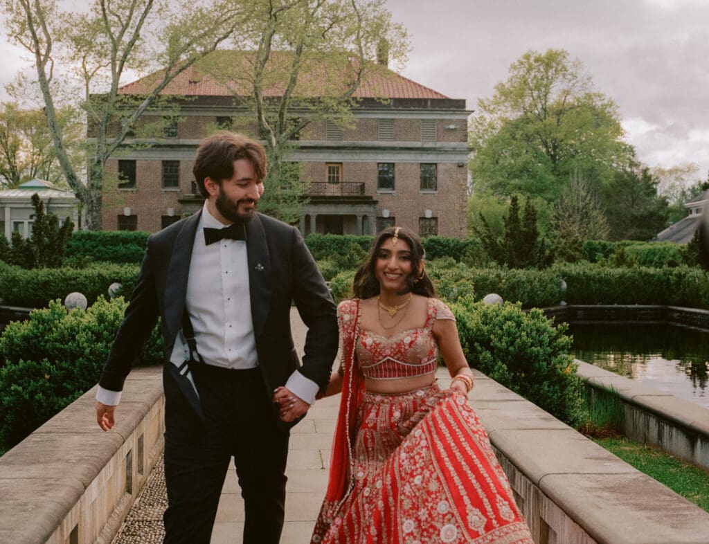 Bride and groom running through a garden holding hands