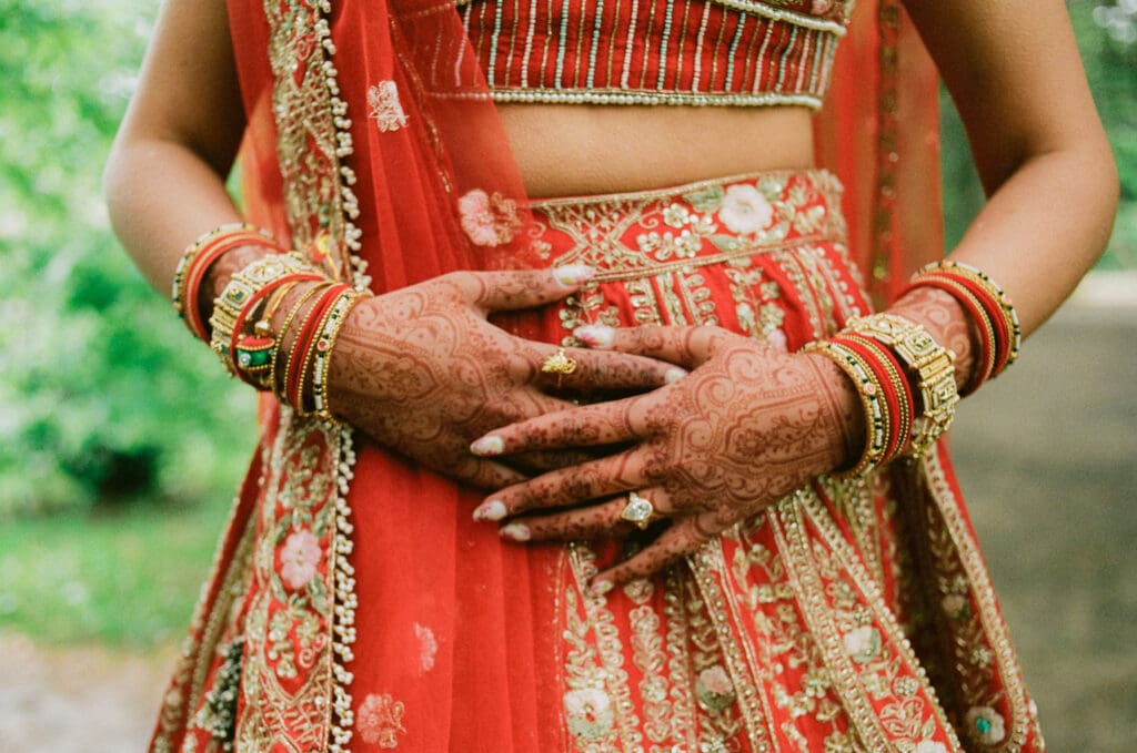 Close up of the bride's hands with henna, jewelry, and wedding attire