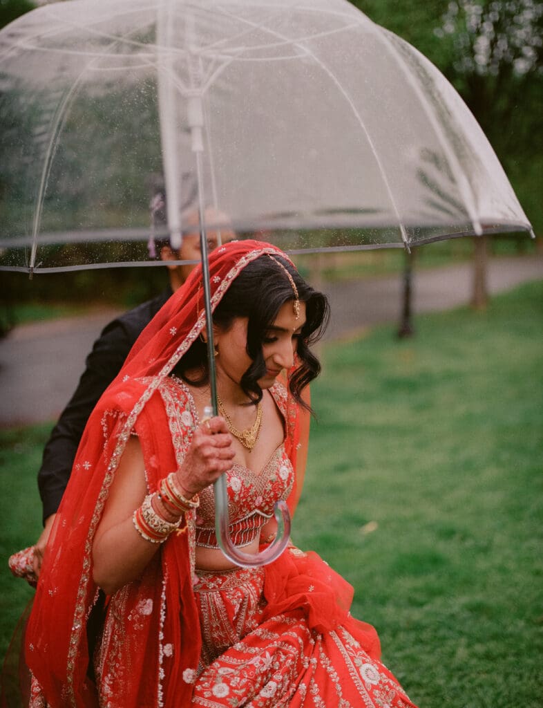 Bride walking to the first look with an umbrella at a Hindu Jewish wedding