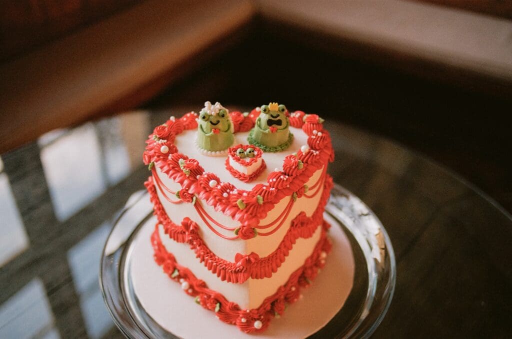 Heart-shaped wedding cake with frog cake toppers