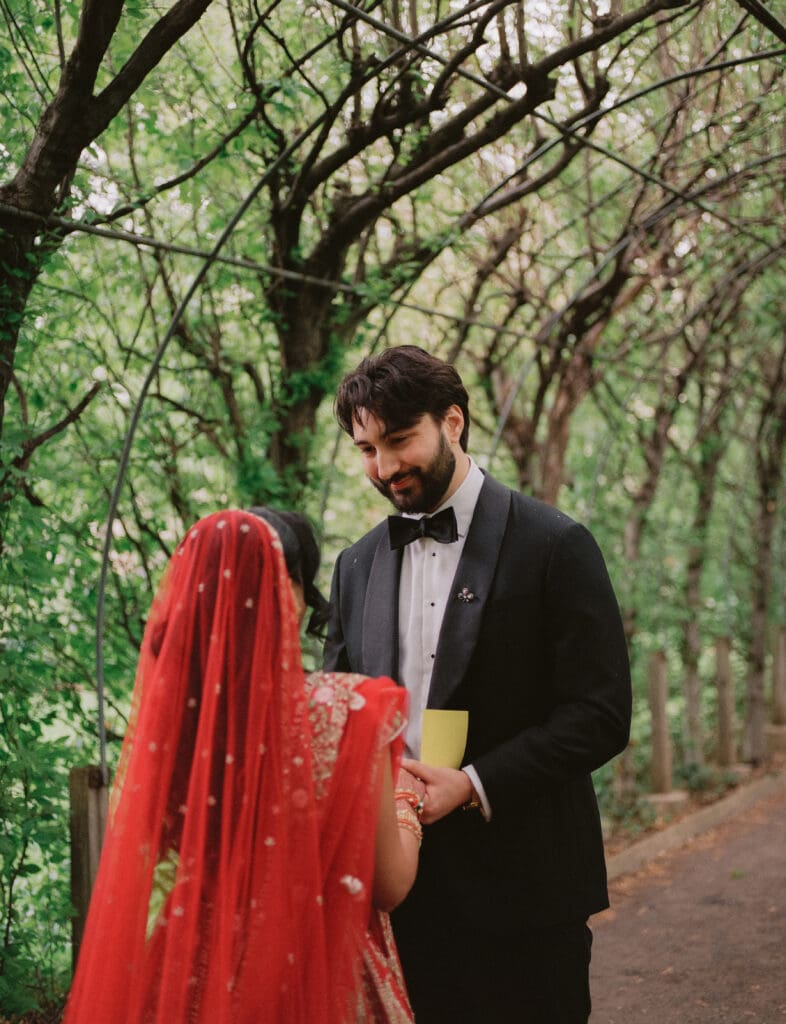 Groom smiles at the bride during the first look at a Hindu Jewish wedding