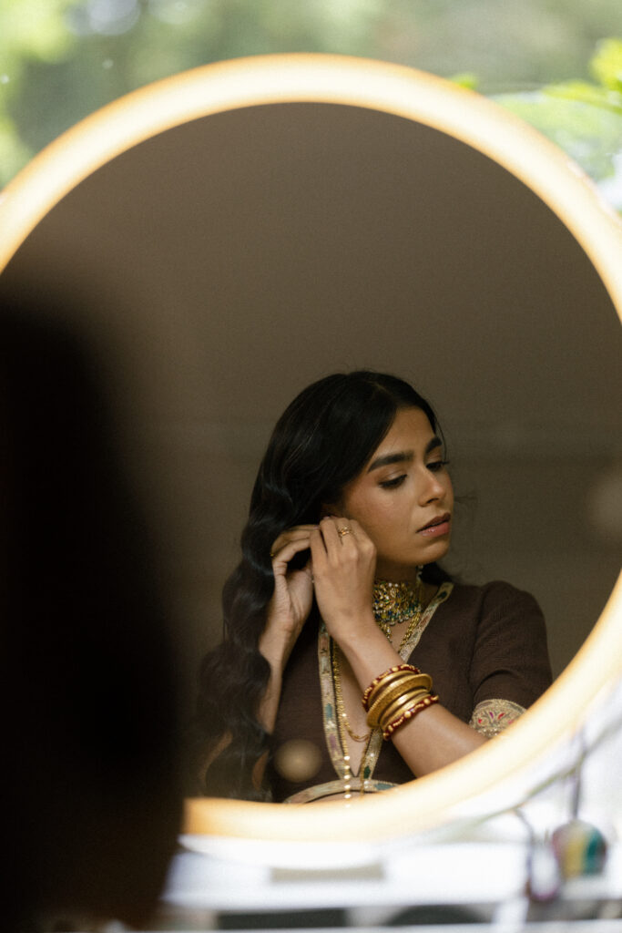 Bride putting on her earrings in the mirror