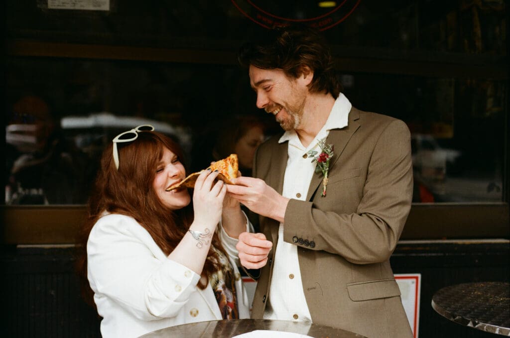 Bride and groom sharing a slice of pizza