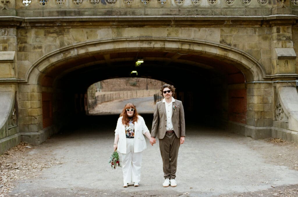 Bride and groom standing in front of a bridge in Central Park