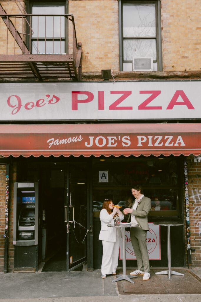 Bride and groom eating a slice of pizza outside Joe's Pizza