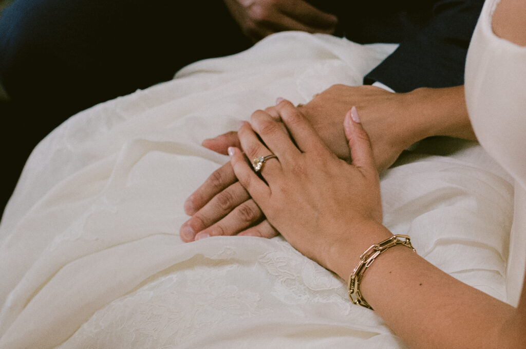 Bride and groom holding hands on the bride's lap
