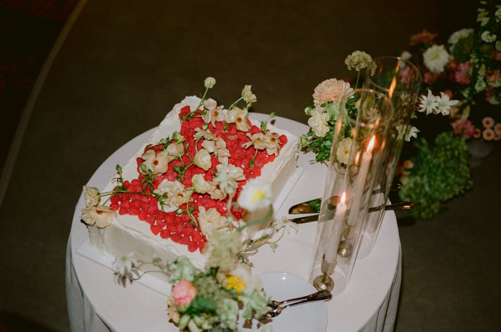 Film photo of wedding cake covered in raspberries and flowers, taken with flash