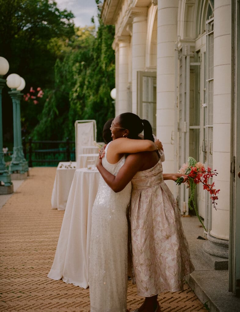 Bride hugging a wedding guest at cocktail hour at a prospect park boathouse wedding