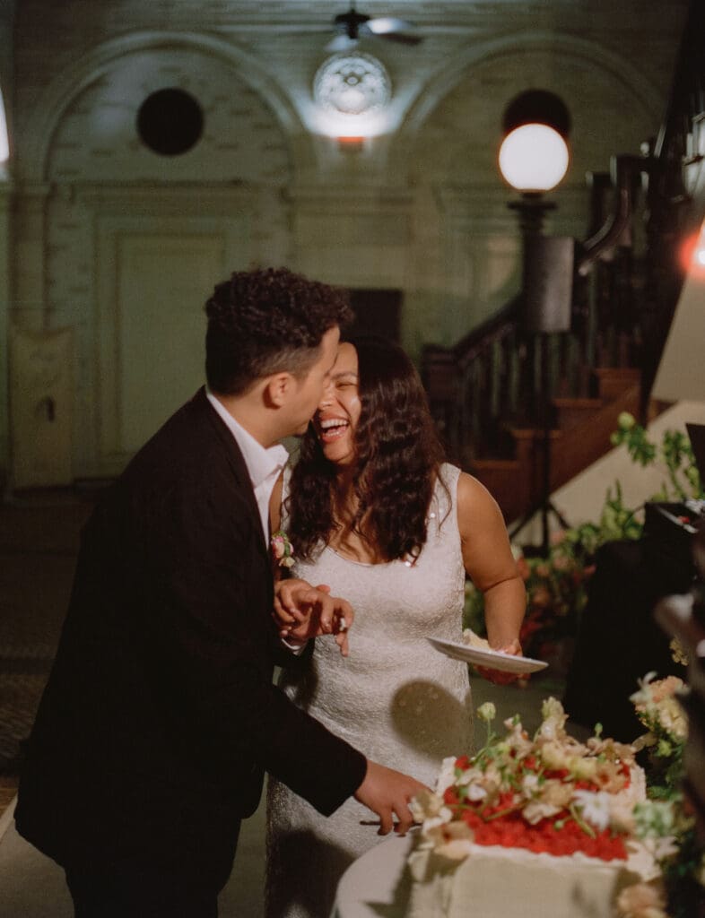 Bride and groom laughing while cutting the cake