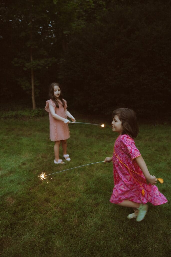 Children running around with sparklers during the wedding reception