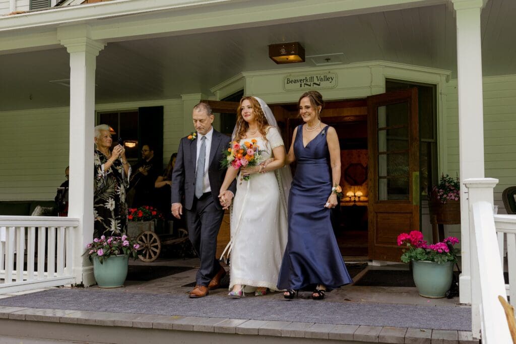Bride walking down the aisle with her mother and stepfather