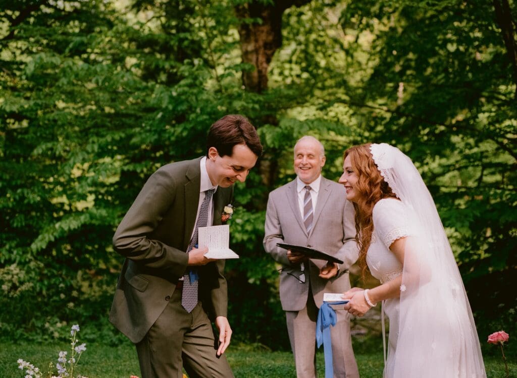 Bride and groom laughing while reading their vows 