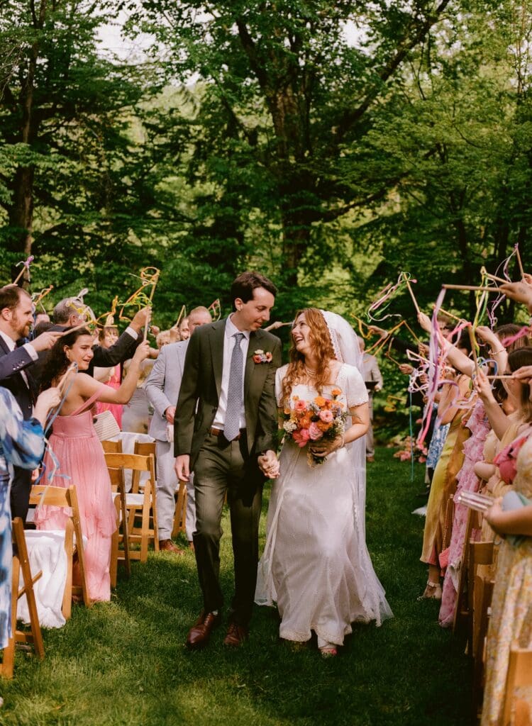 Bride and groom walking back down the aisle with a ribbon wand send off