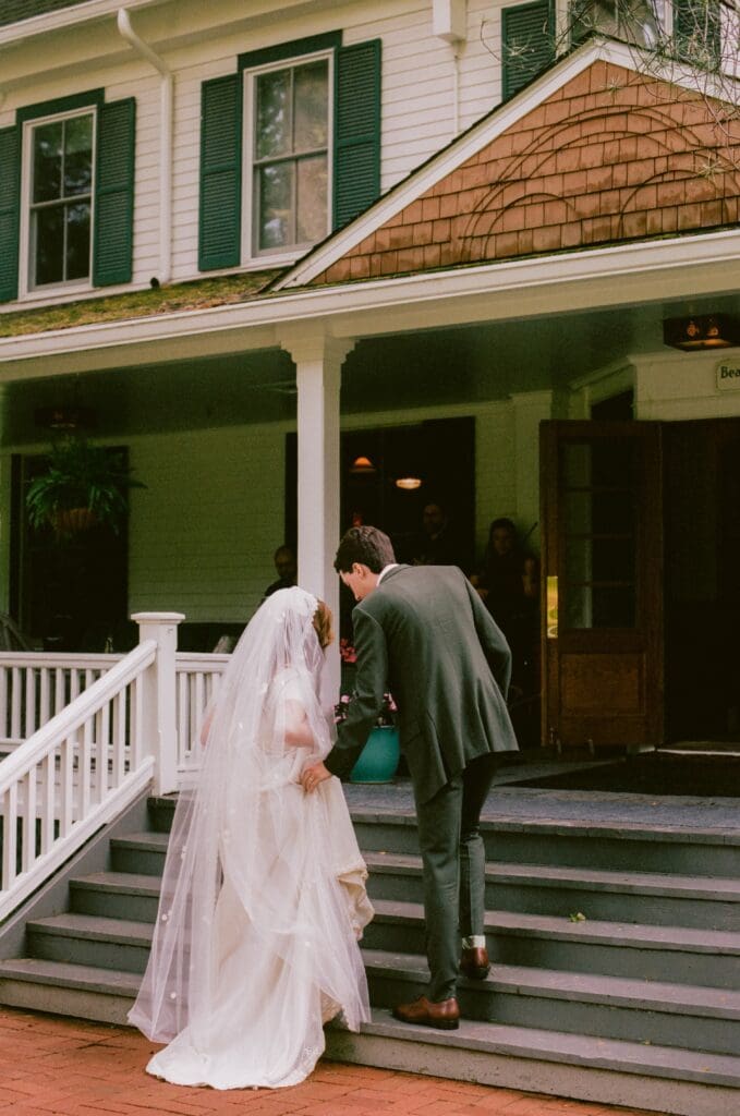 Groom helping the bride walk up the front steps of Beaverkill Valley Inn