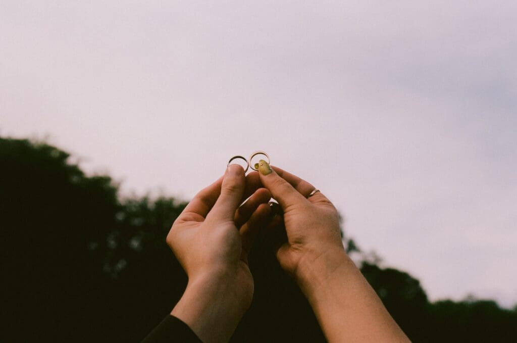 Bride and groom holding the wedding rings in front of the sky