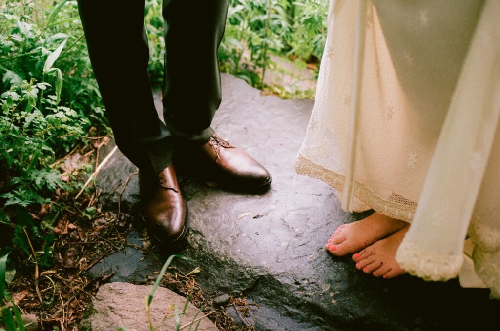 Close up of the bride and groom's feet on a rock by a creek 