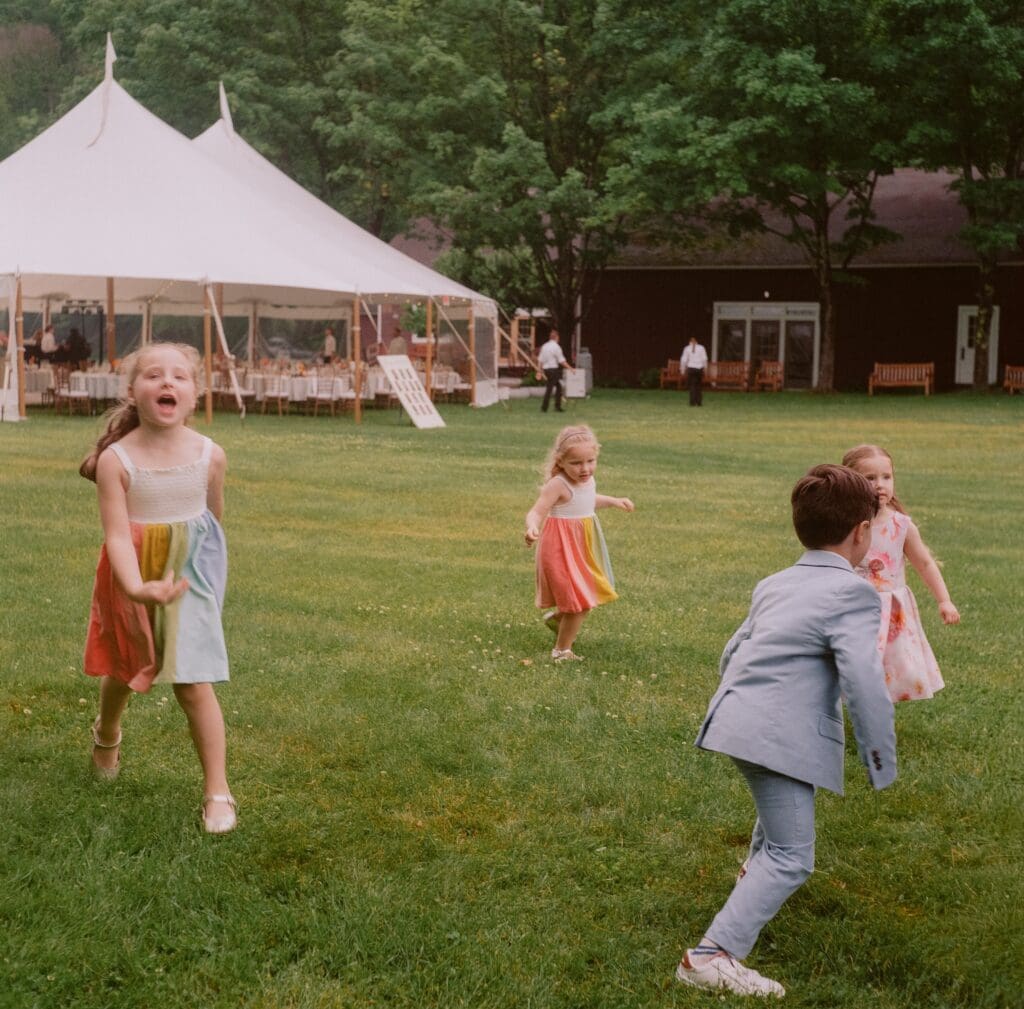 Kids running around on the grass at a wedding reception