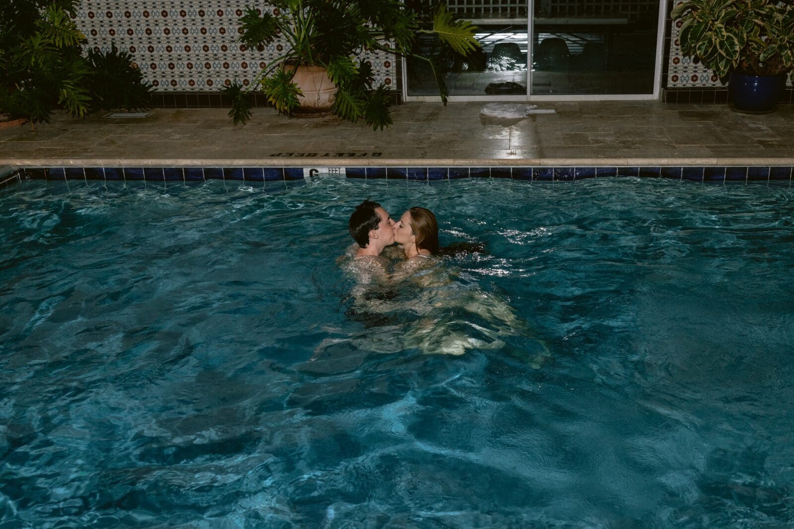 Bride and groom kissing in a pool 