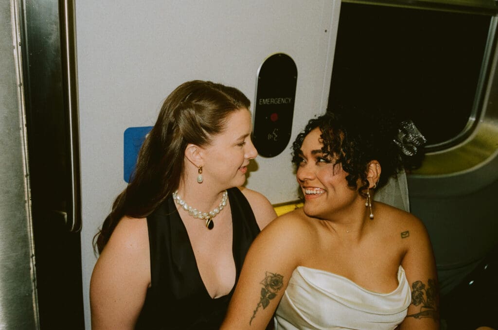Brides smiling at each other on the subway