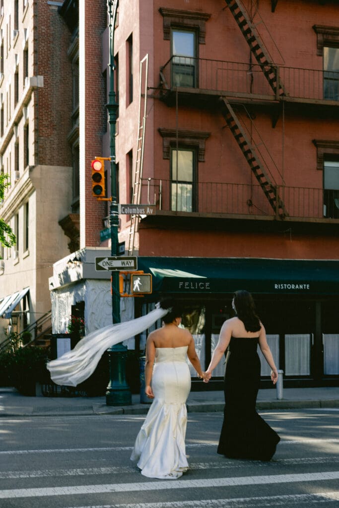 Brides crossing the street to their wedding reception, with the restaurant's sign in the background