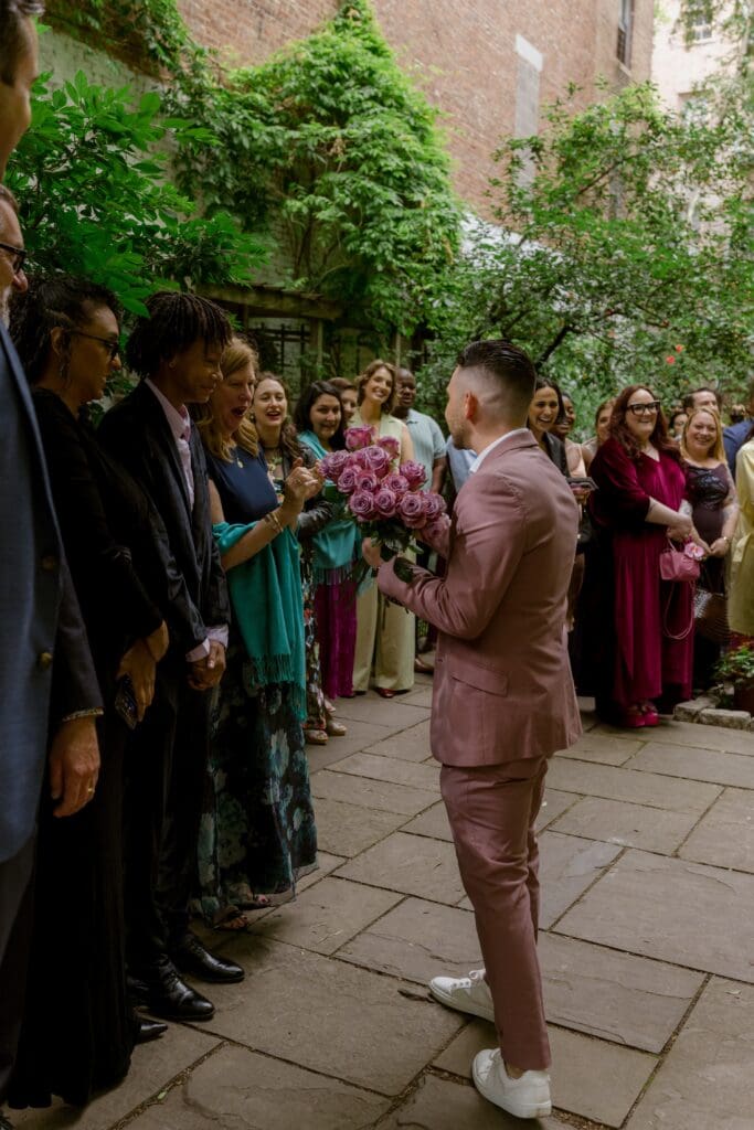 Flower boy handing out roses to wedding guests at a New York City garden wedding
