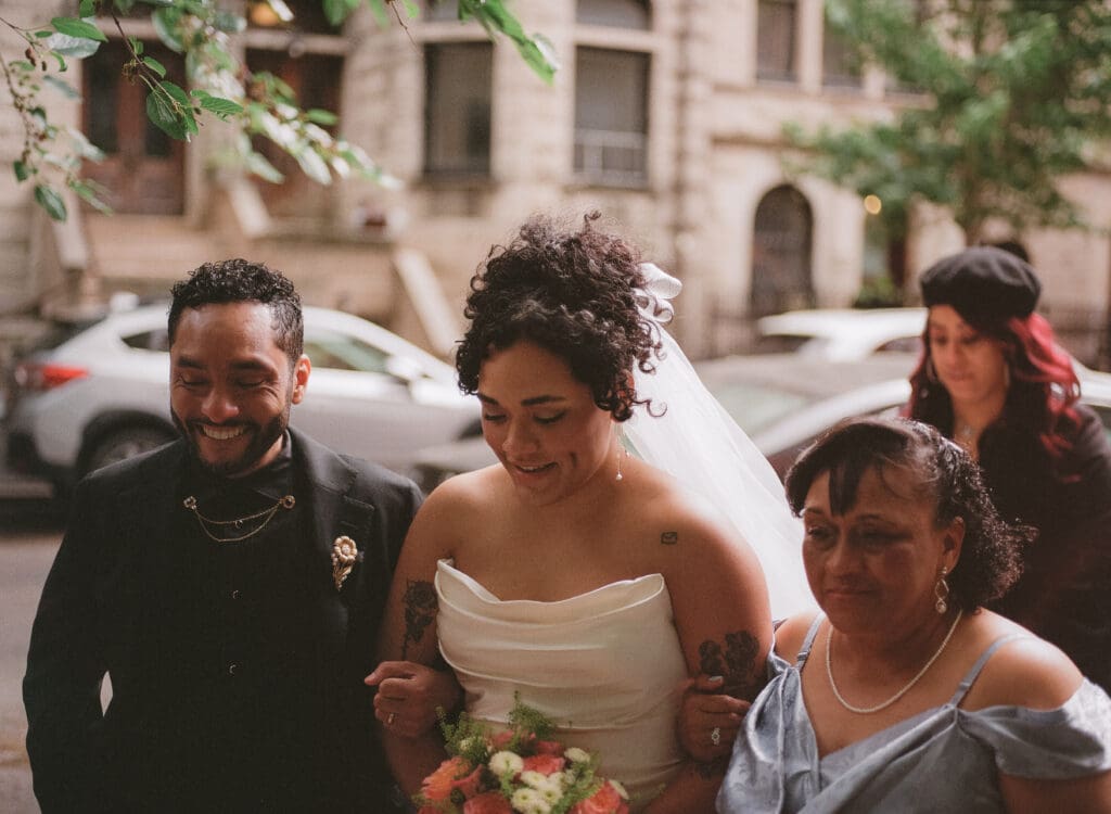 Close up of bride walking down the aisle with her mom and brother at a New York City garden wedding