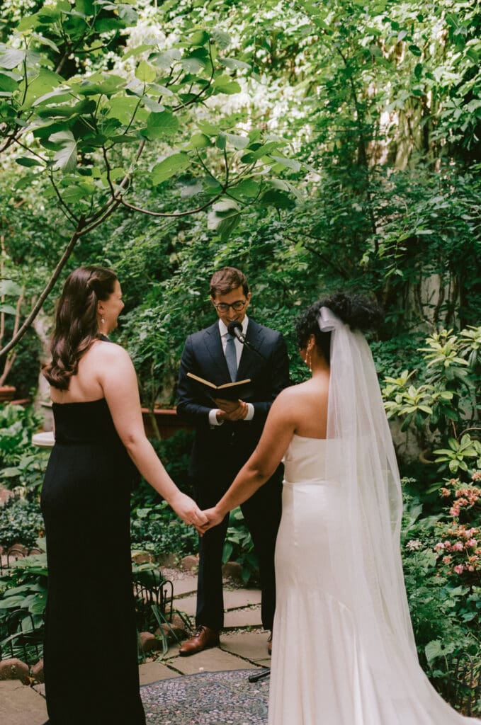 Brides holding hands at the altar at a New York City garden wedding