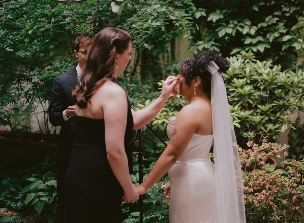 Bride wiping the other bride's tears at the altar at a New York City garden wedding