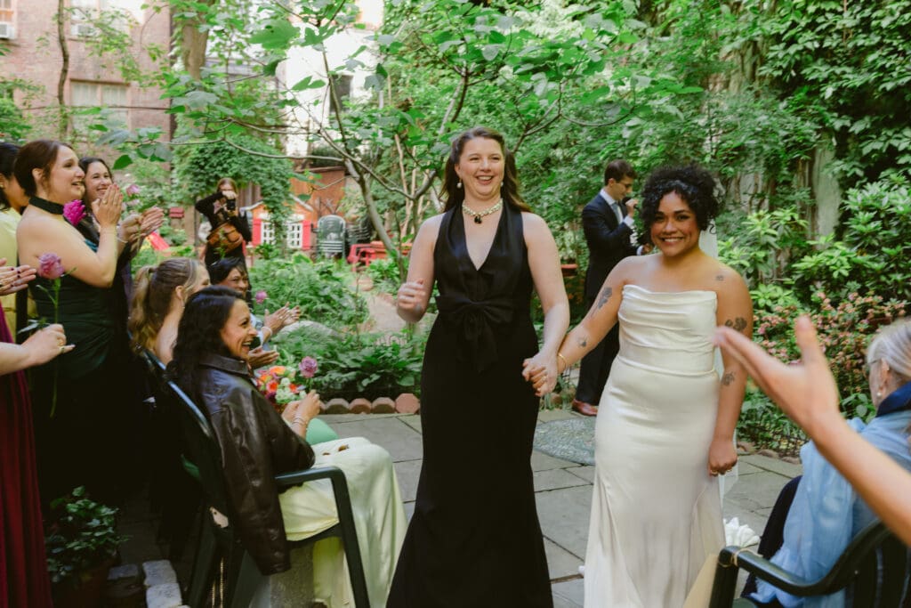 Brides walking back down the aisle together after getting married at a New York City garden wedding