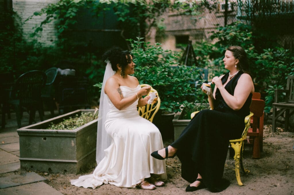 Brides eating ice cream during cocktail hour at a New York City garden wedding