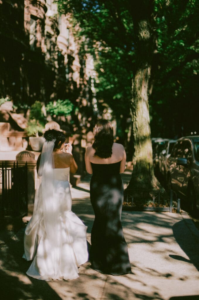 Brides walking down a New York City street lined with brownstones 