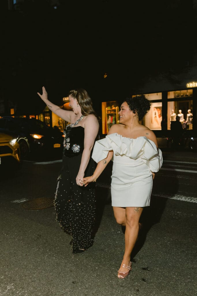 Brides smiling and waving while crossing the street