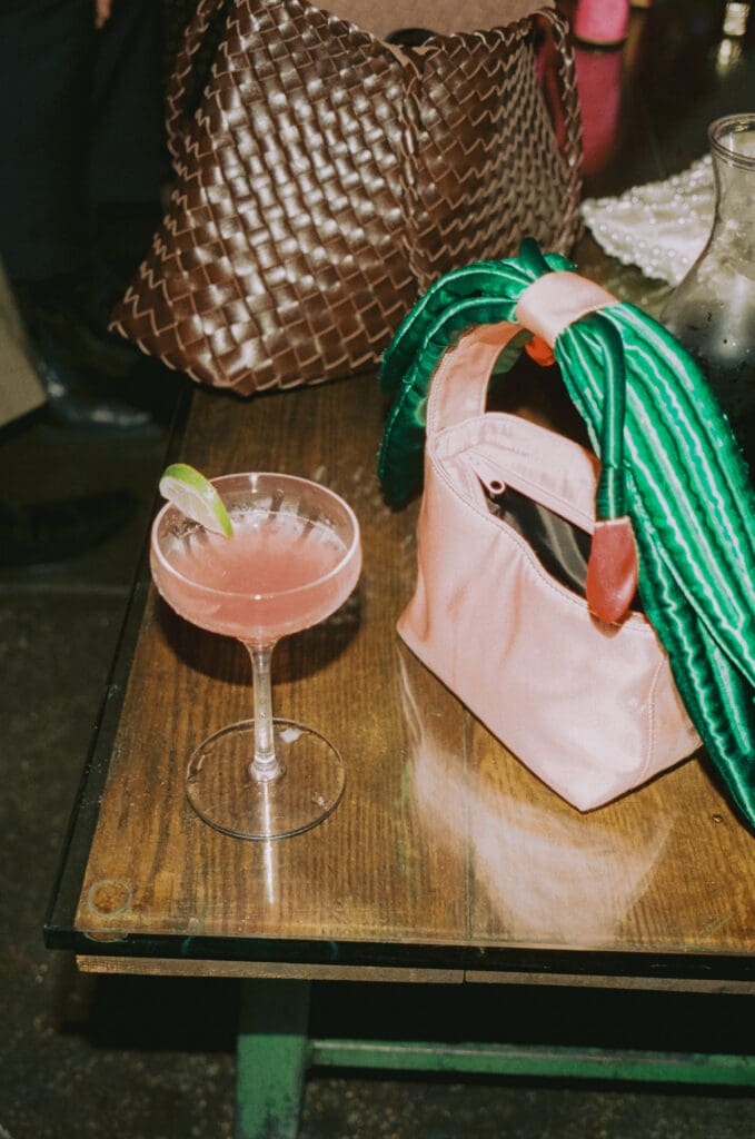 Close up of a wedding guest's cocktail and purse at the afterparty