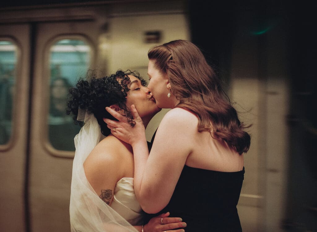 Brides kissing as a train rushes by in the subway station
