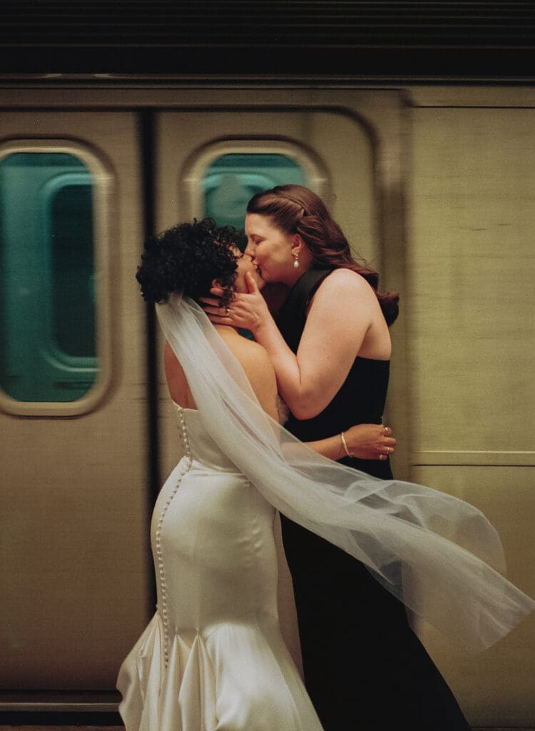 Brides kissing as a train rushes by in the subway station