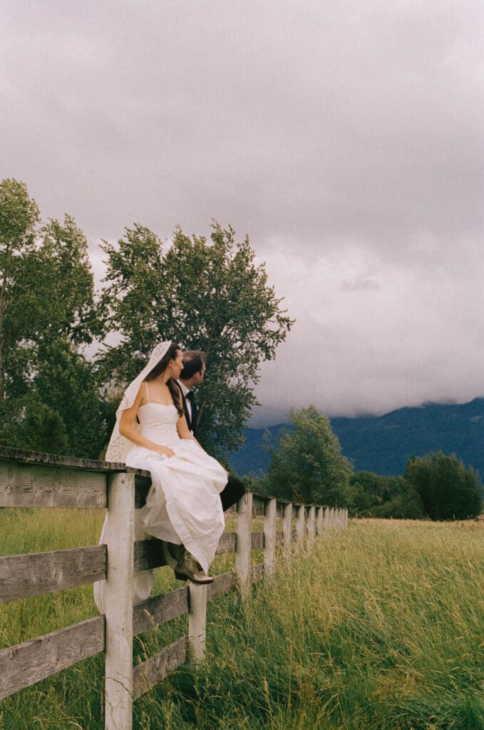 Bride and groom sitting on a field looking away