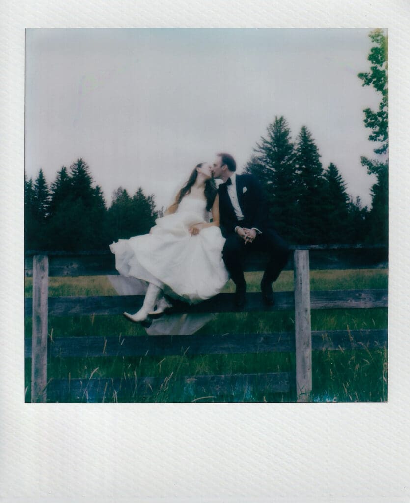 Polaroid of bride and groom kissing on top of a fence