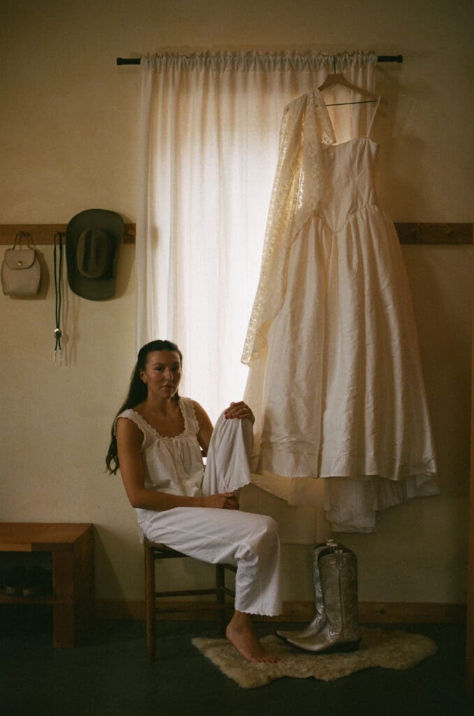 Bride sitting next to her wedding dress