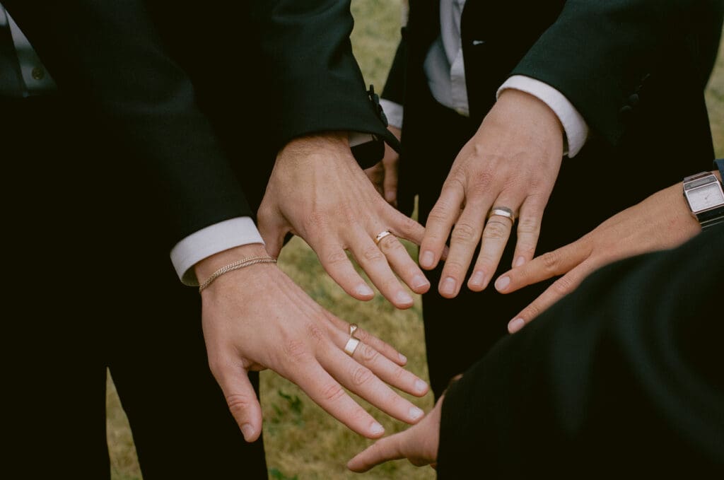 Groom and groomsmen holding out their hands to show off their rings