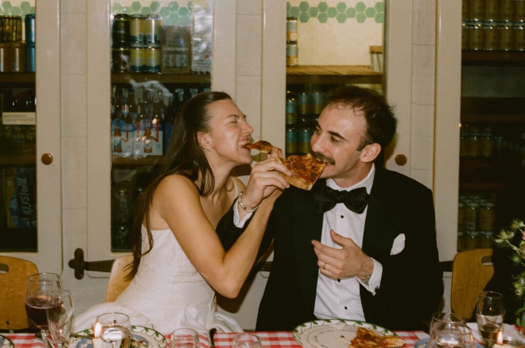 Bride and groom eating pizza during the wedding reception dinner