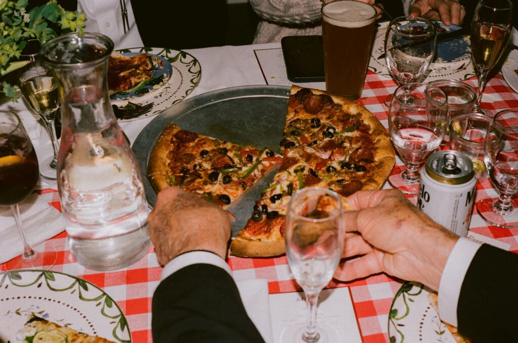 Hands grabbing pizza at a wedding reception dinner