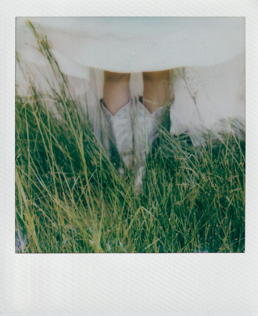 Close up of bride's cowboy boots in the grass