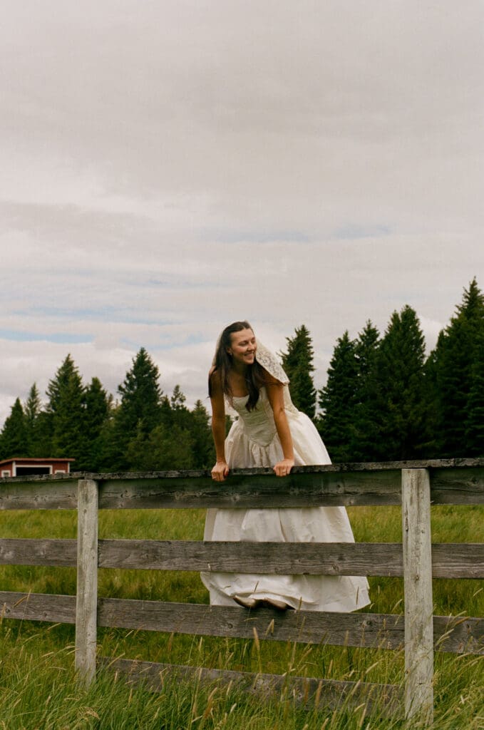 Bride hanging over a fence in a field